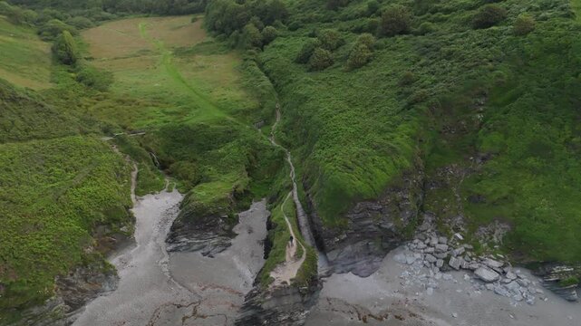 Aerial view of Lansallos Beach with green cliffs and crashing waves in Looe, Cornwall, United Kingdom.