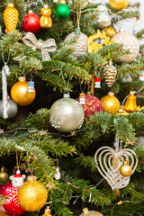 Fototapeta premium A Christmas tree stands with many colorful ornaments hanging from its branches. Each ornament shows different shapes and colors, celebrating the festive season and bringing joy to the home.