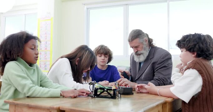 Teacher guides diverse students during a STEM robotics lesson in the classroom. Back to school concept featuring teamwork, hands-on learning, technology, creativity and education