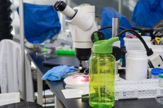 Laboratory workbench with microscope, petri dish, and water bottle