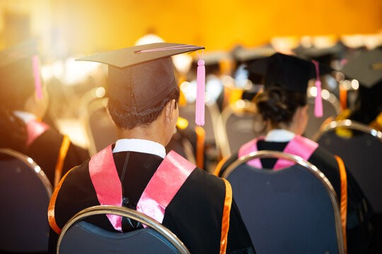 University graduates in vibrant academic gowns and mortarboard caps gather during a glowing cinematic commencement ceremony celebrating educational achievement.