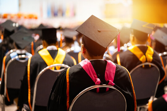 University graduates in vibrant academic gowns and mortarboard caps gather during a glowing cinematic commencement ceremony celebrating educational achievement.