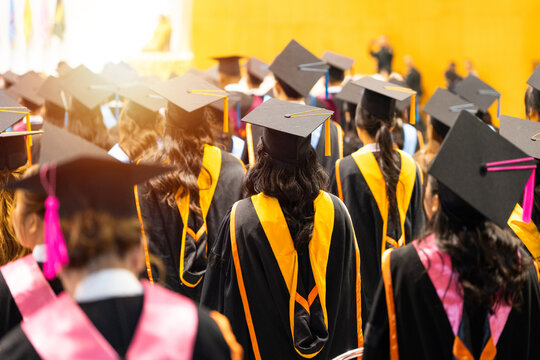 University graduates in vibrant academic gowns and mortarboard caps gather during a glowing cinematic commencement ceremony celebrating educational achievement.