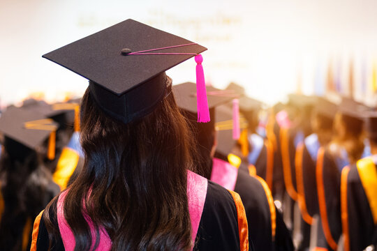 University graduates in vibrant academic gowns and mortarboard caps gather during a glowing cinematic commencement ceremony celebrating educational achievement.