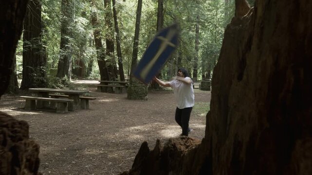 Professional Athlete Spinning Painted Board in Redwood Forest Picnic Area - Wide, Steady Cam Shot