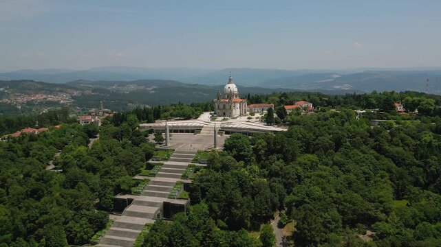 Aerial view of the Sanctuary of Our Lady of Sameiro with its grand staircase and neoclassical architecture surrounded by lush green forests in Braga, Braga, Portugal.