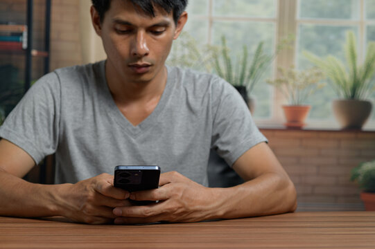Young Man Using Smartphone at Table in Bright Modern Indoor Space