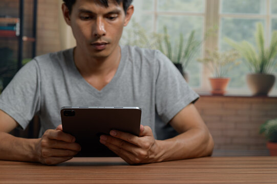 Man Using a Tablet in a Bright Modern Indoor Space with Plants