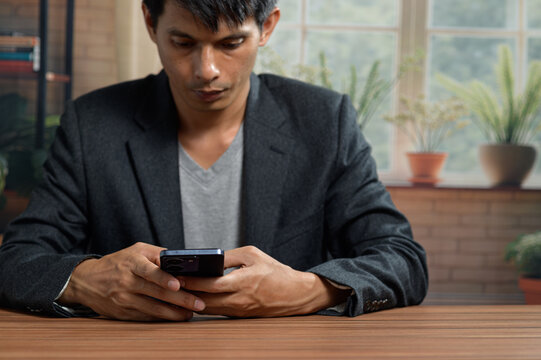 Young Man Using Smartphone at Table in Bright Modern Indoor Setting