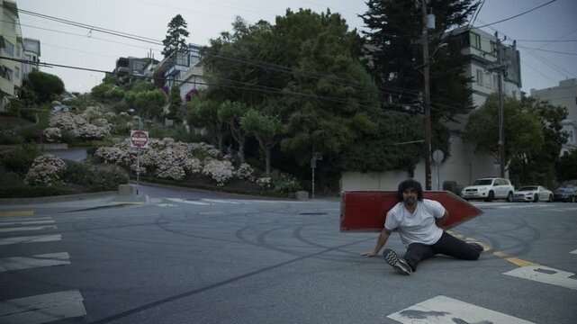 Man Doing Cartwheel And Splits With Red Board on San Francisco City Street Intersection - Wide Shot