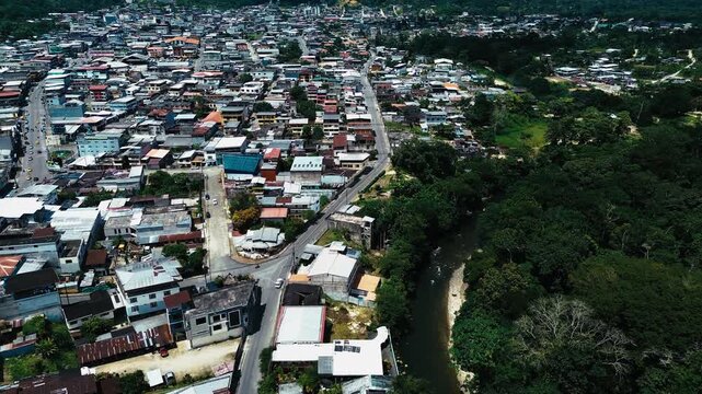 Aerial View of Ecuador Town Beside Winding River and Dense Forest, Urban Buildings, Bridge, Green Trees and Tropical South American Landscape