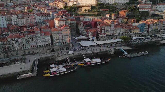 Aerial view of Ribeira do Porto with traditional Rabelo boats docked along the Douro River, historic colorful buildings, and waterfront promenade in Porto, Porto, Portugal.