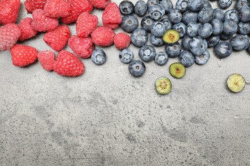 Fresh ripe raspberries and blueberries on grey table, flat lay. Space for text © New Africa