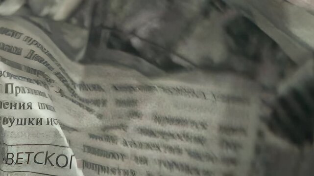 Hands delicately interact with crumpled newspaper, showcasing the texture and layers of the paper. This artistic exploration breathes life into everyday objects by revealing their hidden beauty.