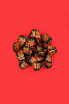 Tartan red green ribbon bow Scottish design. Vivid contrast abstract decorative background. Giving object for greeting card, birthday, anniversary.