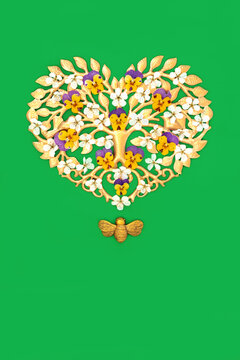 Gold heart tree shape decoration, blossom, pansy flowers with bee ornament on green background.