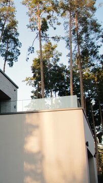 Vertical video. Time lapse of fast-moving tree shadows across a modern house brick facade.