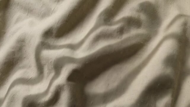 This is a of folded clothing on a bed with white sheets and brown comforter.
