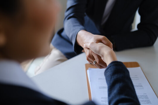 Close up of business people shaking hands after signing a contract agreement in a professional meeting.