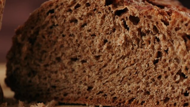 Black rye bread close up, cutting with knife dark brown sliced loaf, borodinsky slavic food, square slices with coriander on white background, baker with tasty healthy fresh bread.