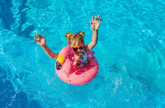 A child swims in a pool surrounded by flamingos. Selective focus.
