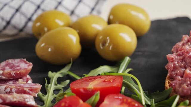 Snack plate beef tartar, cherry tomatoes, green olives and fuet sausage, jamon. Wine snack. High quality 4k footage