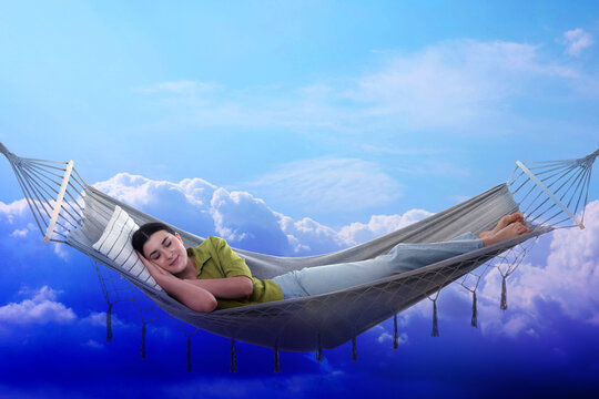 Young woman sleeping in hammock against bright sky