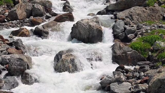 Fast alpine meltwater cascades through a rocky creek bed near Sustenpass in summer, Switzerland.