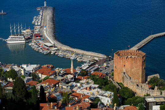 Beautiful panoramic view from above of ancient Red Tower Kizil Kule and coastal harbor with boats and lighthouse in Alanya Turkey, famous historical travel landmark and resort destination