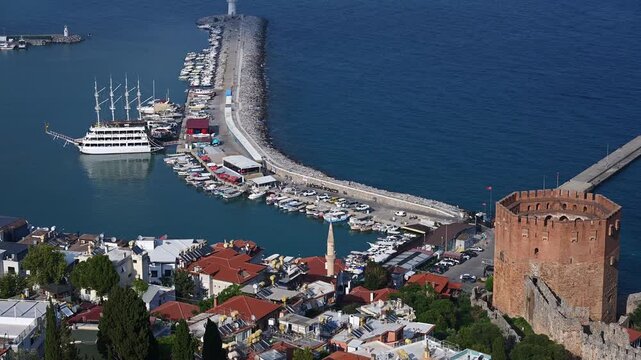 Beautiful panoramic view from above of ancient Red Tower Kizil Kule and coastal harbor with boats and lighthouse in Alanya Turkey, famous historical travel landmark and resort destination