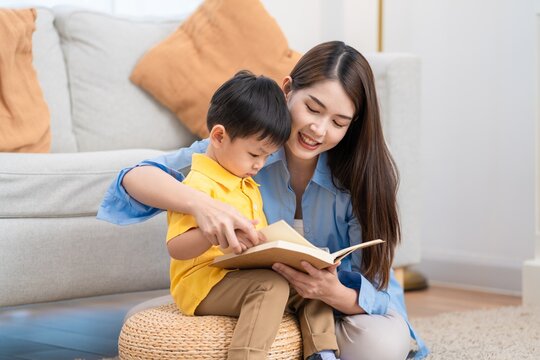 Mother and son share a moment reading a book together in their living room during the afternoon