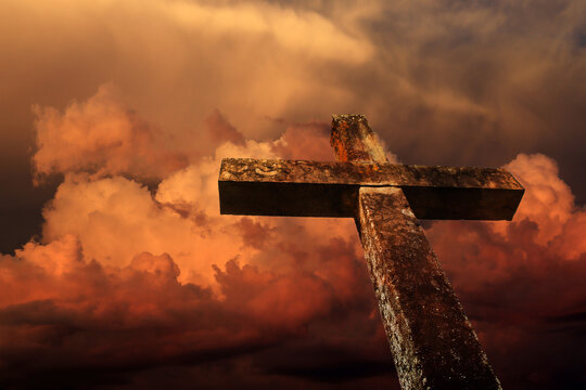 Ein steinernes Kreuz vor einem dramatischen gelb-orangen Himmel