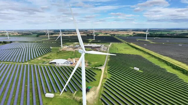 Aerial view of Chelveston Renewable Energy featuring rows of solar panels and wind turbines in the countryside of Chelveston, England, United Kingdom.
