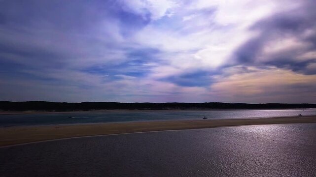 Reflective coastal sandbar under dramatic evening sky