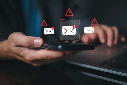 Close up of hands using mobile phone displaying suspicious email notification icons. Digital safety concept highlighting dangerous malware risks, internet fraud, and cyber attack vulnerability.