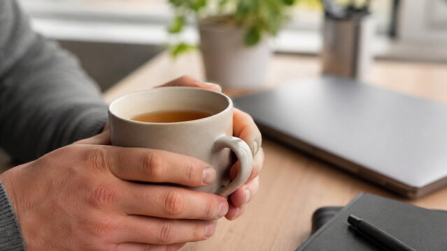 Hands holding warm tea during a calm office work break