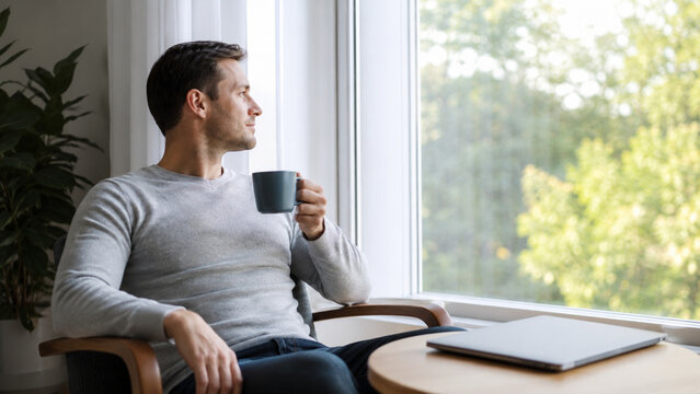 Calm professional taking a tea break beside a bright office window