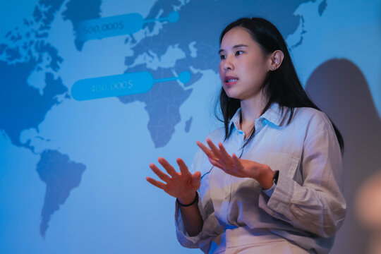 A young businesswoman gestures confidently while presenting a financial analysis slide with growth charts and plan comparisons, illustrating a professional data presentation session