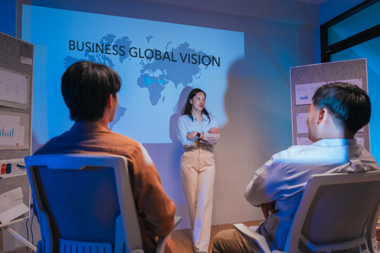 A young businesswoman gestures confidently while presenting a financial analysis slide with growth charts and plan comparisons, illustrating a professional data presentation session