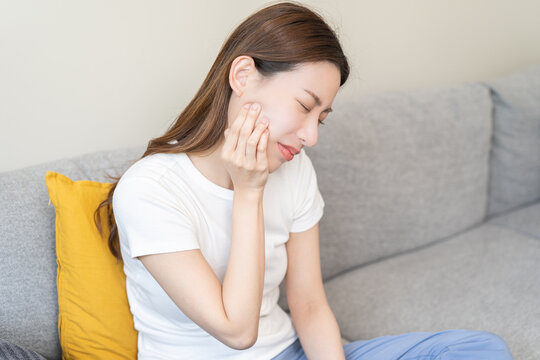 Closing eyes asian young woman hand touching cheek, face expression from toothache, tooth decay or sensitivity, Having tooth or teeth problem or inflammation, suffering from health. Sensitive teeth.