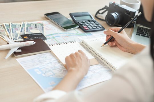 Travel planning, vacation, holiday trip concept, asian young tourist woman hand take note to check travel date on calendar and information for booking hotel online, ticket preparing for journey trip.