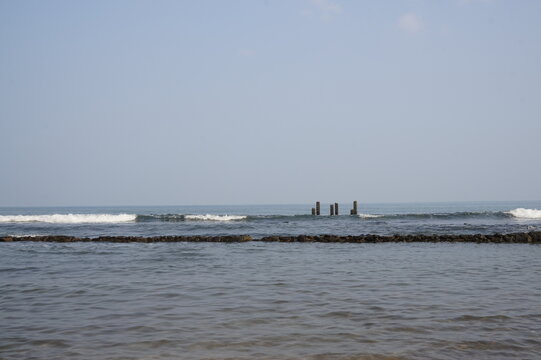 Beautiful ocean seascape with stone breakwater and old wooden pillars