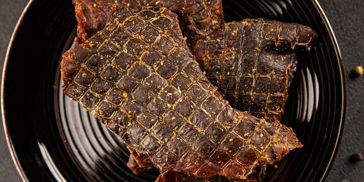 Beef jerky spiced dried meat natural healthy food tasty snack fresh delicious gourmet food background on the table, rustic food, top view, copy space