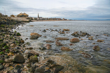 Fototapeta premium East end of Portobello beach in Edinburgh, overcast autumn day, Joppa parish church tower visible at distance