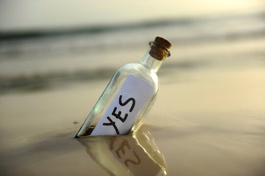 Affirmative response sent. Bottle on the beach with an affirmative response inside, yes, positive message. Misty beach landscape background with soft colors and gradients.