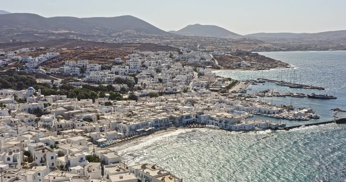 Naousa Paros Greece Aerial v3 panoramic pan shot capturing small fishing village with charming whitewashed buildings surrounded by beautiful aegean sea against mountainous background - September 2021