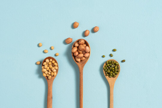 Three wooden spoons filled with different types of beans