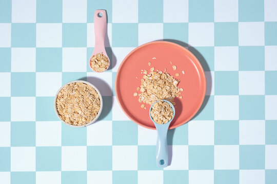 Rolled oats are scattered on a coral plate with measuring spoons 