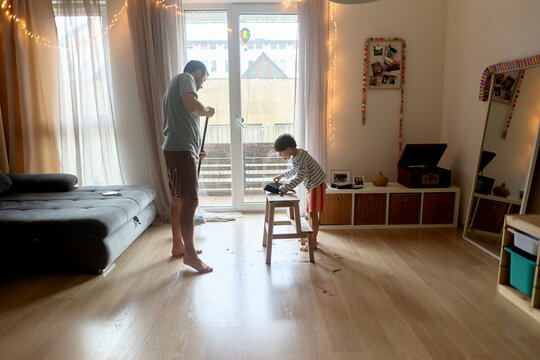 Father sweeping hair after son&rsquo;s home haircut