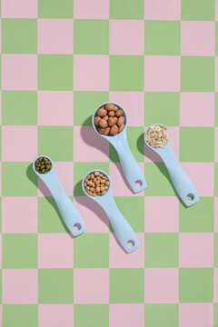 Four light blue measuring spoons filled with different nuts and beans